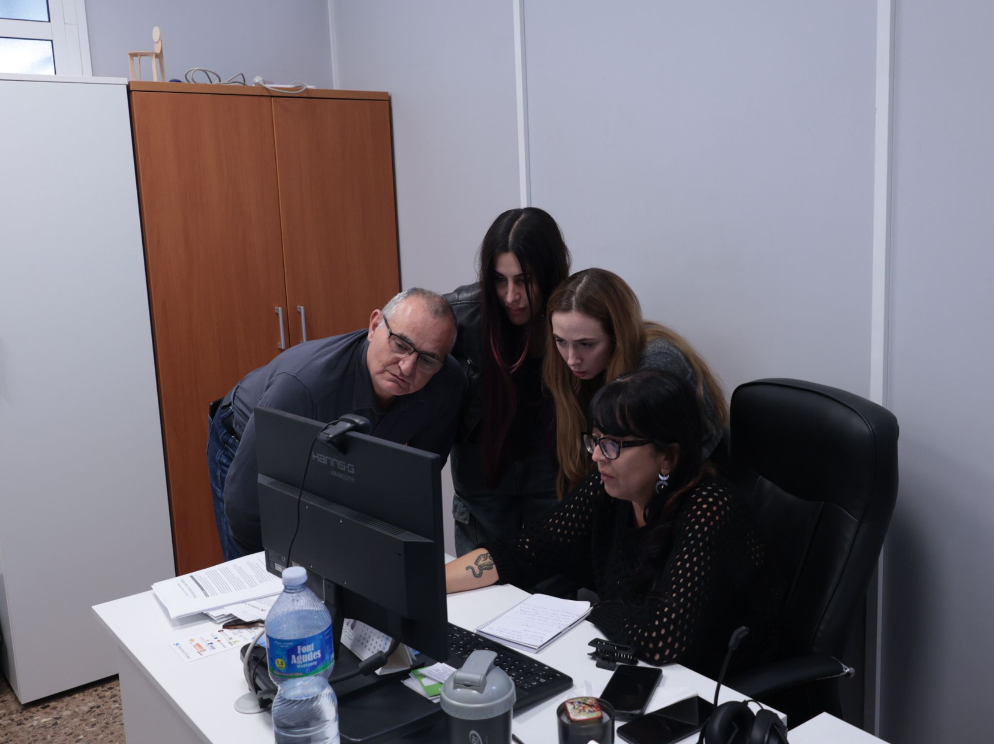 Grupo de cuatro personas trabajando juntas frente a un escritorio, concentradas en el mismo ordenador