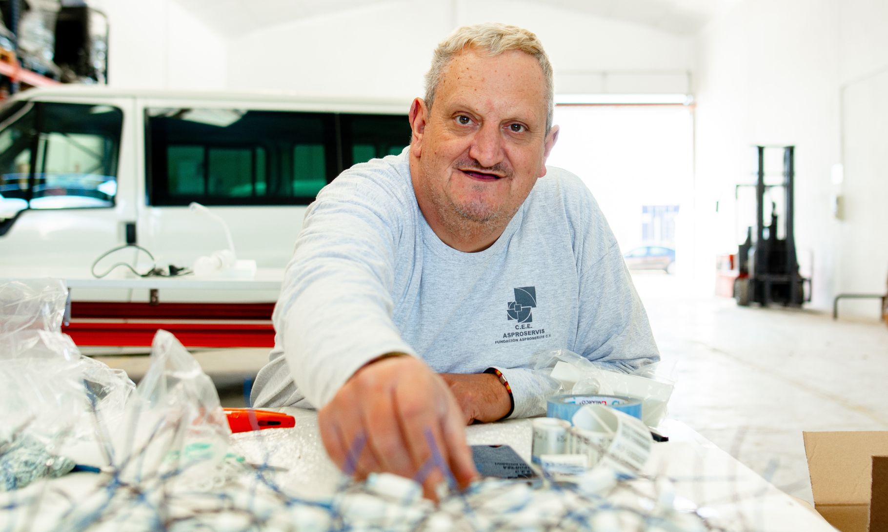 Persona sonriente trabajando en una mesa dentro de un almacén