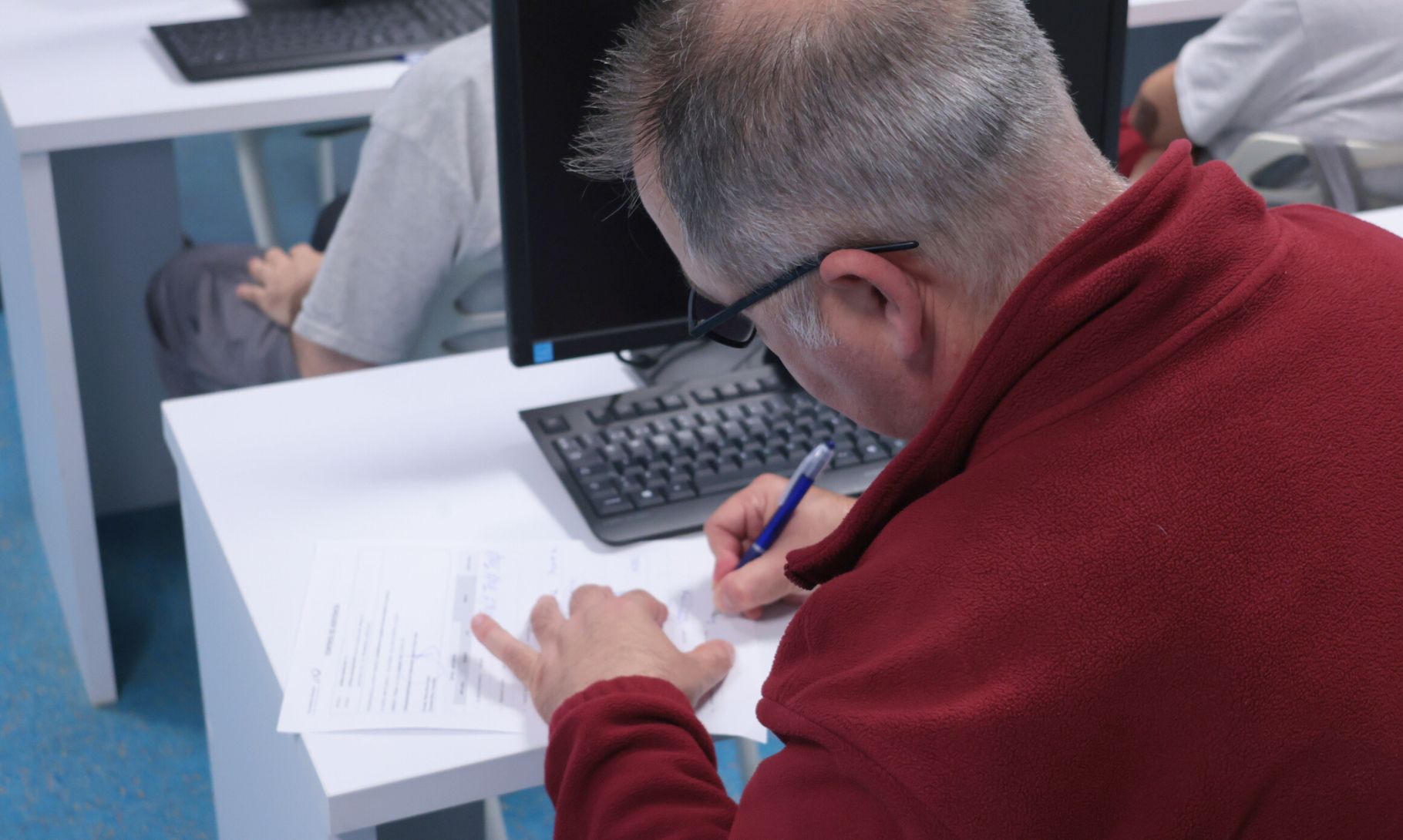 Persona escribiendo en un formulario en un escritorio de oficina, vista de espaldas