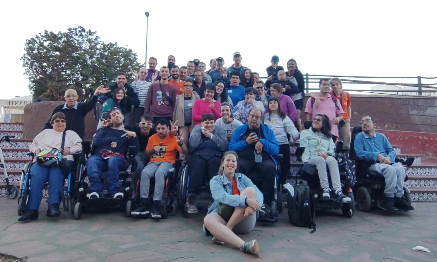 Grupo diverso de personas, entre ellas trabajadores de Asprona, personas en silla de ruedas y personas con discapacidad intelectual, al aire libre frente a unas escaleras