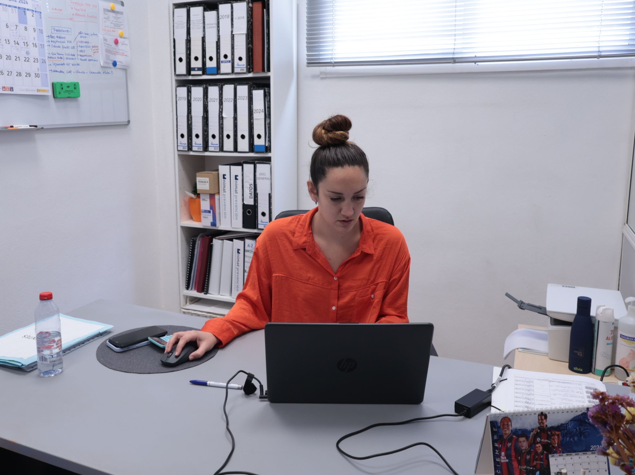 Persona concentrada trabajando en un escritorio con un ordenador portátil en una oficina